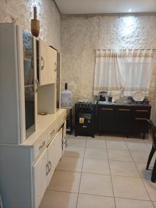 a kitchen with white cabinets and a stove at Sol & mar Hospedagem - Boqueirão Sul Via Balsa Cananéia in Ilha Comprida