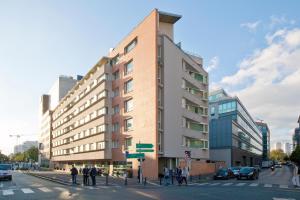 a building on the corner of a city street with people at Séjours & Affaires Montreuil Saint Mandé in Montreuil