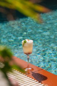 a drink sitting on a table next to a swimming pool at Hotel Shoshana - Adults Only in Eilat