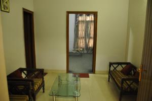 a living room with two chairs and a glass table at Hotel Pratiksha in Morādābād
