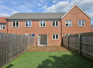 a brick house with a wooden fence and a yard at Gloria's Getaway in Langport