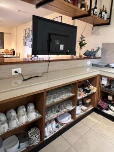 a kitchen with a tv and a shelf with dishes at Chapelet Hostal in Tababela