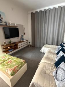 a hotel room with two beds and a flat screen tv at Sobrado 3 Praias in Ubatuba