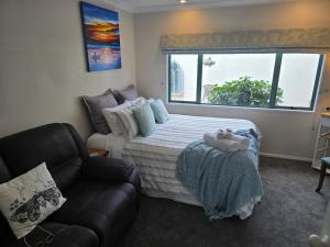 a bedroom with a bed and a couch and a window at Island View in Tauranga