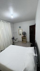 a bedroom with a white bed in a room at Apartamento no centro de Mongaguá in Mongaguá