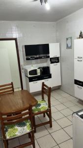 a kitchen with a table and two chairs and a stove at Apartamento no centro de Mongaguá in Mongaguá