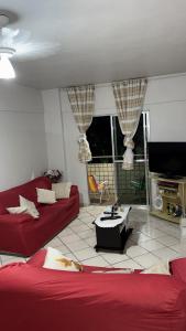 a living room with a red couch and a tv at Apartamento no centro de Mongaguá in Mongaguá