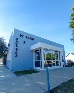 a white building with a sign that reads de driveway at Hosteria Posada Drake in Puerto San Julián