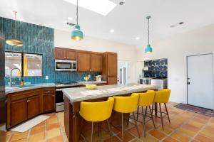 a kitchen with wooden cabinets and yellow bar stools at Moroccan Desert Oasis -Salt Pool - Spa - Games in Bermuda Dunes +61 photos