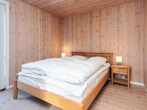 a bed in a room with a wooden wall at 4 star holiday home in Ulfborg in Fjand Gårde