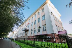 un bâtiment rose et blanc avec une clôture noire dans l'établissement Hotel Inju, à Taraz