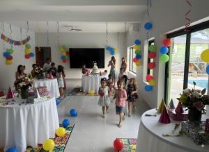 a group of children walking in a room with balloons at MeMe's Place in Placencia +113 photos