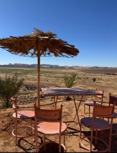 a table and chairs and an umbrella in the desert at Riad Nomad in Foum Mharech +19 photos