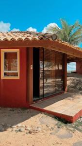 a small red house with a window and a palm tree at Apoena in Conde