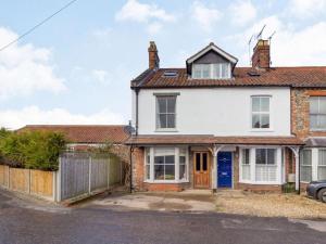 an exterior view of a white house with a blue door at 3 Bed in Holt oc-87147 in Holt