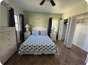 a bedroom with a bed and two dressers and two windows at The Palms apt 1 in Cedar Grove +6 photos