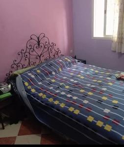 a bed with a blue and yellow comforter in a bedroom at Maison zakaria in Meknès