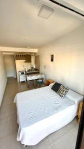 a bedroom with a large white bed and a kitchen at Descanso Céntrico in Salta