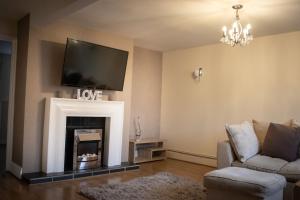 a living room with a fireplace with a tv above it at 6 Bed home near to Birmingham Nec Airport 6 miles from city centre in Marston Green