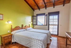 a bedroom with a bed and two windows at Complejo rural Alhelí - Apartamentos y habitaciones in Valdredo