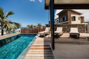 a swimming pool with chaise lounge chairs next to a house at Villa de Luxe avec Piscine privée chauffée-3 Chambres-Sud Sauvage in Petite Île