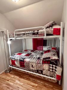 a bedroom with two bunk beds in a room at La Cachette in LʼAnse-Saint-Jean