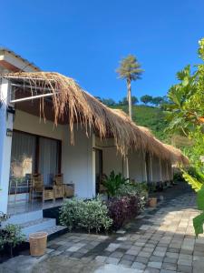 a house with a thatched roof and a patio at Raya Homestay in Kuta Lombok