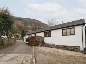 a white house with a stone wall next to a road at Jasmine Cottage in Keswick
