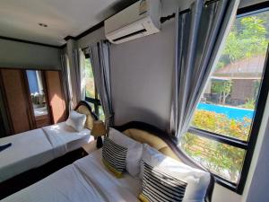 a bedroom with two beds and a large window at Rim Khao Jungle Resort Koh Lanta in Ko Lanta +135 photos