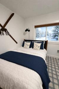 a bedroom with a bed with blue sheets and a window at High Pines Haven in Angel Fire
