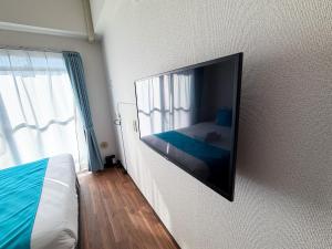 a bedroom with a flat screen tv on the wall at BALCOM STAY Hiroshima Takasu in Hiroshima