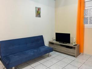 a blue couch in a living room with a tv at La Belle Escapade in Quartier du Fond Fleuri