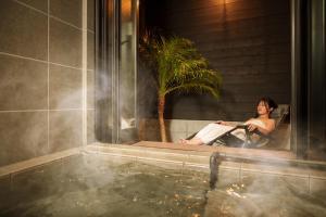 a woman sitting in a chair next to a hot tub at 湯宿灯火 in Beppu