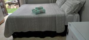 a bed with a white blanket and two towels on it at Pousada Ruby in Irati