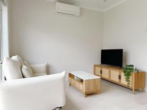 a living room with a white couch and a tv at Modern Home Canal Berwick in Berwick