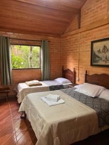 a bedroom with three beds in a room at Pousada Chalés Vida Verde in Bom Jardim de Minas