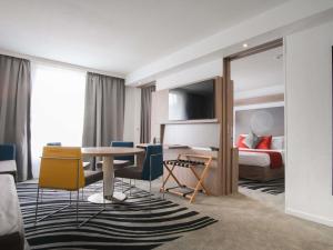 a hotel room with a bed and a table and chairs at Novotel Narbonne Sud A9/A61 in Narbonne