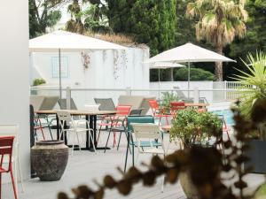 an outdoor patio with tables and chairs and umbrellas at Novotel Narbonne Sud A9/A61 in Narbonne