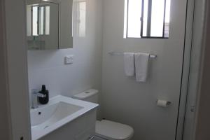 a white bathroom with a sink and a toilet at Lunar Cabins in Parkes +14 photos