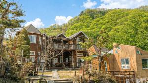 a large house with a mountain in the background at Gapyeong Solle Spa Pension in Gapyeong