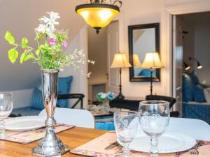 a table with glasses and a vase with flowers on it at 4 star holiday home in Skanderborg in Skanderborg