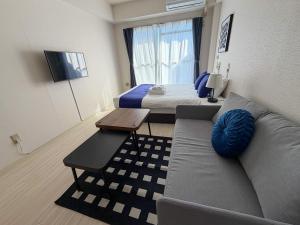 a living room with a couch and a bed at BALCOM STAY Hiroshima Takasu in Hiroshima