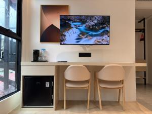 a desk with two chairs and a tv on a wall at Goldlight Inn in Miri