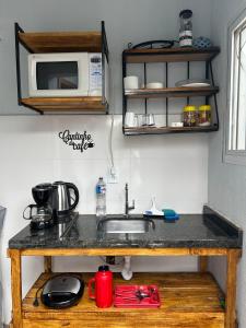 a kitchen counter with a sink and a microwave at Cantinho do Descanso in Cascavel