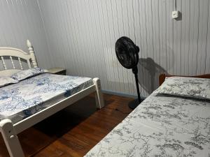 a room with two twin beds and a fan at Cantinho do Descanso in Cascavel