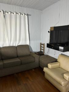 a living room with a couch and a flat screen tv at Cantinho do Descanso in Cascavel