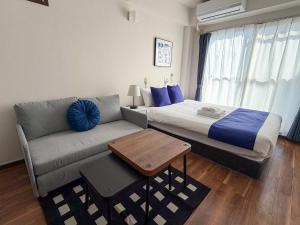 a bedroom with a bed and a couch and a table at BALCOM STAY Hiroshima Takasu in Hiroshima