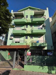 a green building with a fence in front of it at Apto Completo Ar e Wi-Fi Parque Itaimbe in Santa Maria