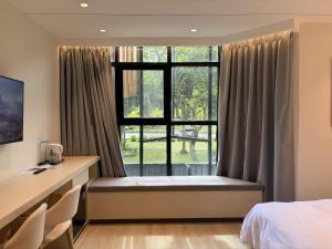 a bedroom with a window with a desk and chairs at Goldlight Inn in Miri