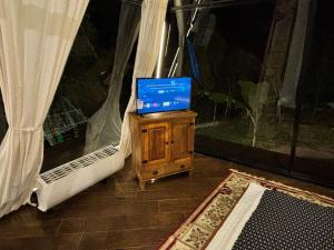 a television on a wooden stand in a room with a bed at Piramidevidro in Santa Isabel